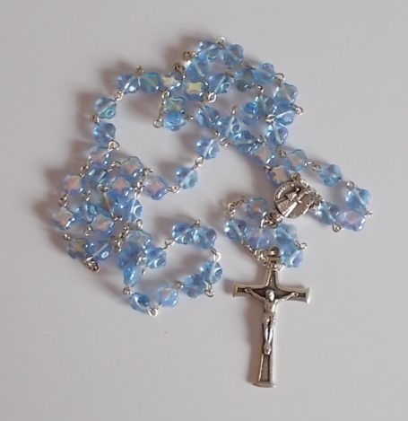 Perlenrosenkranz in Blau mit einem Silberkreuz.