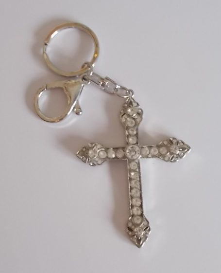 Kreuzanhänger mit Strasssteinen an einem Schlüsselring.
