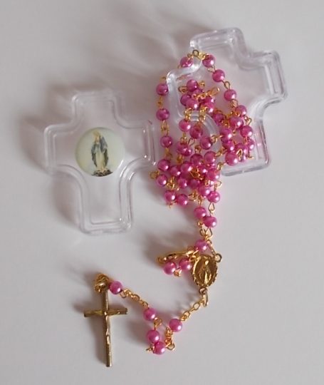 Rosenkranz mit pinken Perlen und goldenem Kreuz, umgeben von transparenten Kreuzen.