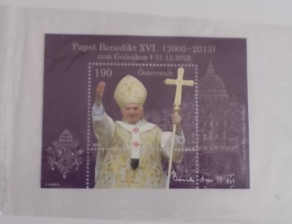 Briefmarke von Papst Benedikt XVI., mit goldener Kreuz und dem Petersdom im Hintergrund.
